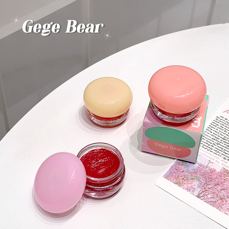 Three small jars of lip balm with a pink box labeled 'Gege Bear' on a white surface.