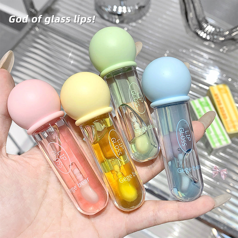 Four lip glosses in pastel colors held in a hand with a metallic background.