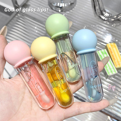 Four lip glosses in pastel colors held in a hand with a metallic background.