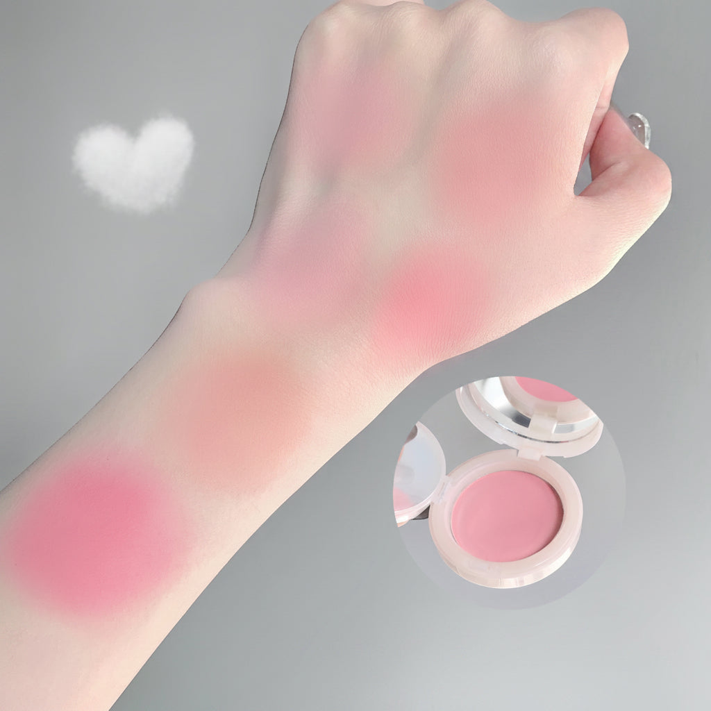 Hand with pink blush on wrist next to open blush compact