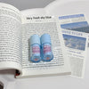 Two blue bottles labeled 'Brother Bear' on an open book with a newspaper on a gray background.