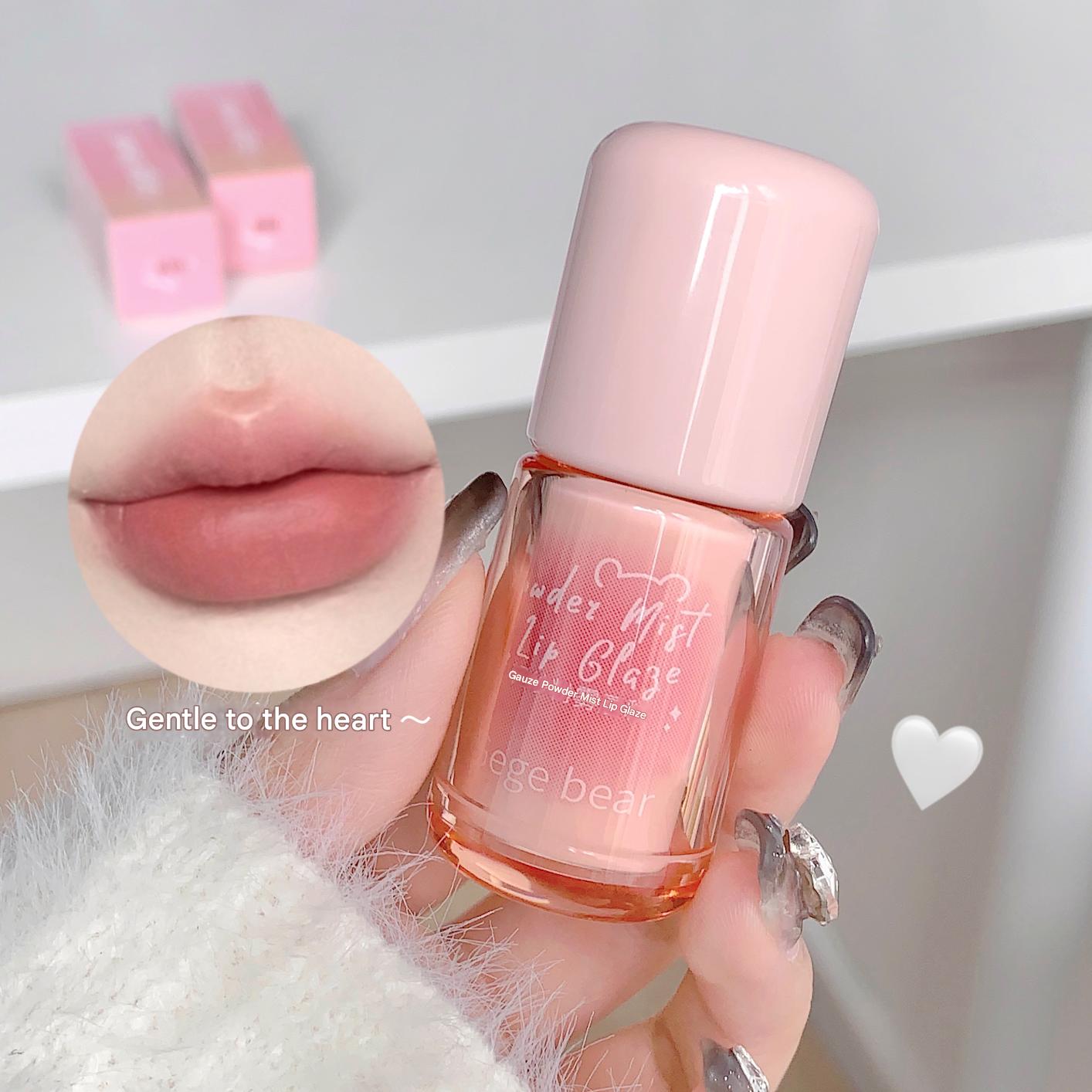 Pink lip gloss bottle held by a hand with a close-up of lips and text 'Gentle to the heart' on a light background.