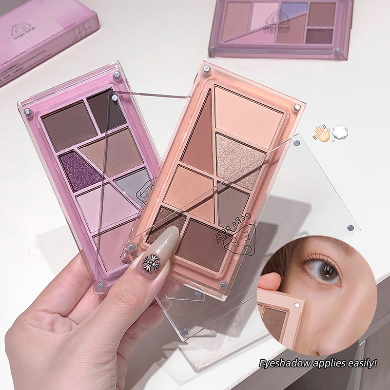 Makeup eyeshadow palettes with a hand holding one, on a light background.