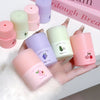 Set of small cosmetic containers with colorful lids held by a hand on a white surface.