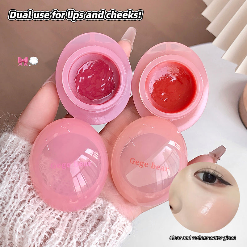 Pink lip balm with dual use for lips and cheeks, held by a hand.