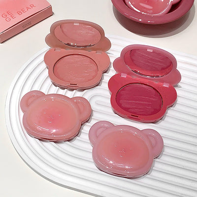 Pink makeup products with bear design on a white surface
