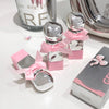 Silver perfume bottles with pink bows on a white surface