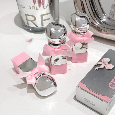 Silver perfume bottles with pink bows on a white surface