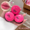 Three pink lip products with 'Girl Bear' branding held in a hand, showing a close-up of a glossy pink lip.