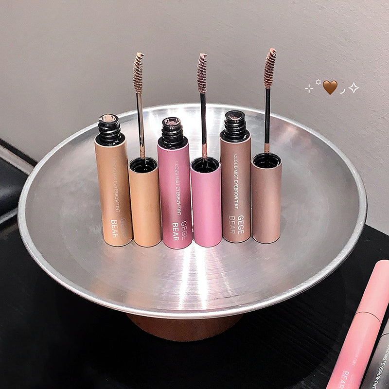 Set of mascara tubes on a metallic tray with a neutral background