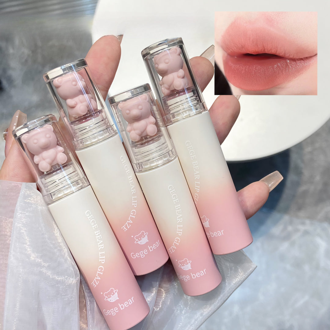 Set of pink and white gradient lip glosses with bear-shaped caps, held by a hand.