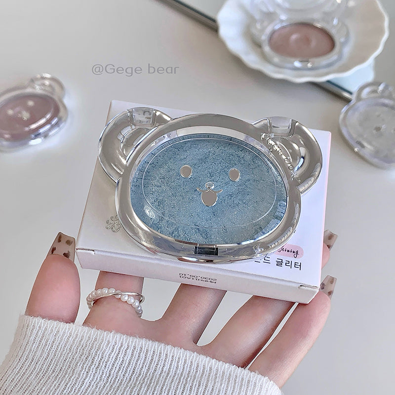 Compact powder with a decorative lid held by a hand on a light background
