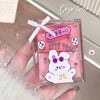 Pink GEGE BEAR product packaging with a white ribbon held by a hand.