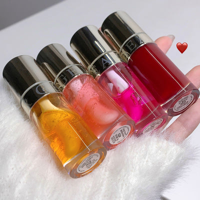 Four nail polish bottles with different colors held by a hand on a white surface.