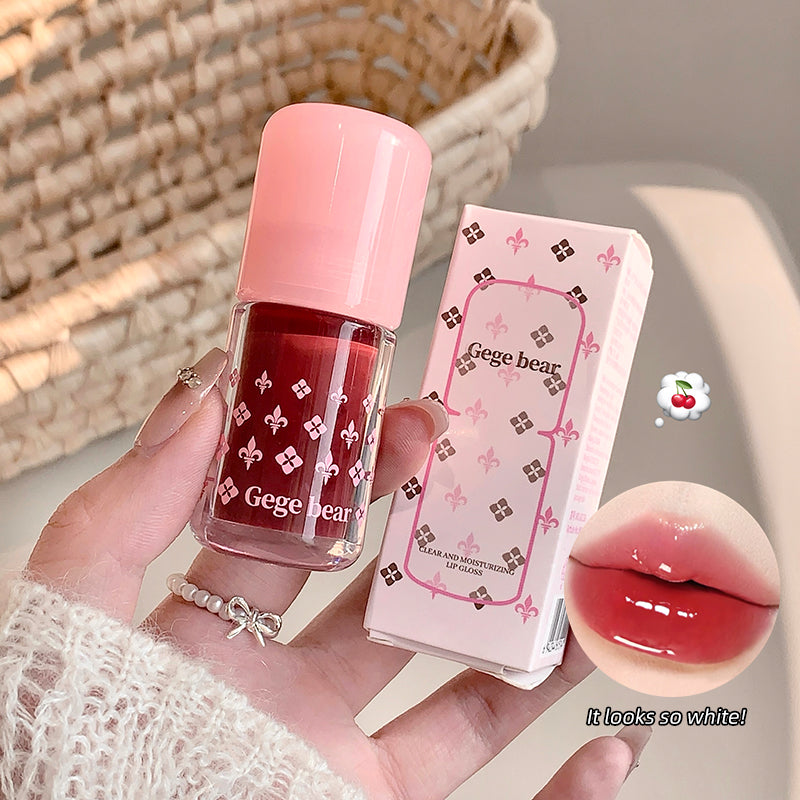 Lip gloss with pink cap and packaging held by a hand, with a close-up of lips wearing the product.