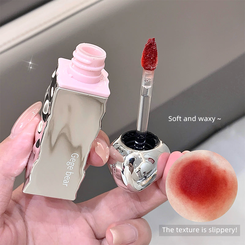 Lip gloss with applicator and texture sample held by a hand