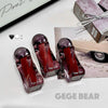 Three red bottles with purple caps labeled 'GEGE BEAR' on a white surface.