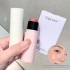 Hand holding a pink makeup stick with a white container and 'Gege bear' packaging on a gray background.