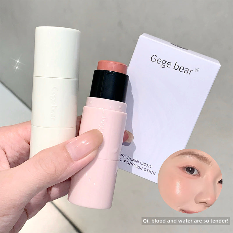 Hand holding a pink makeup stick with a white container and 'Gege bear' packaging on a gray background.