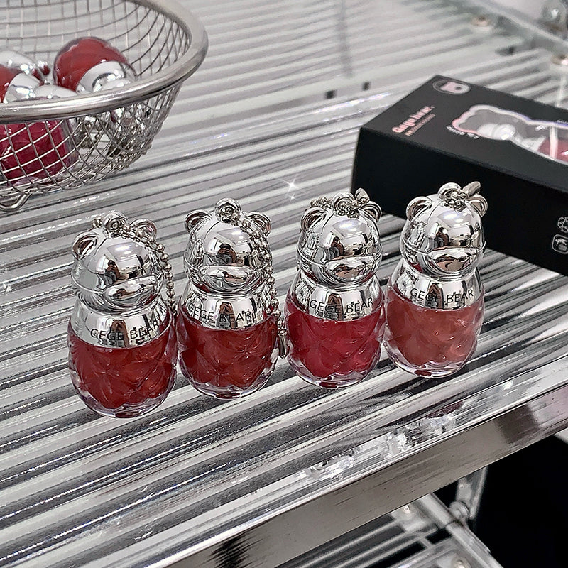 Four small bear-shaped containers with red liquid on a metallic surface.