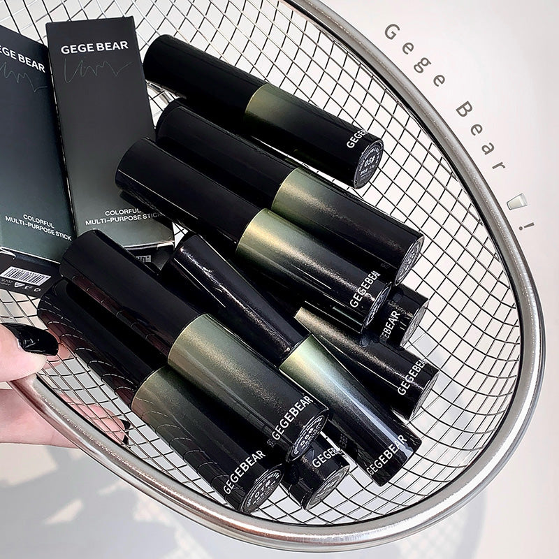 Black and green GEGE BEAR lip products on a metal grid surface.