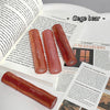 Three Gege bear lip glosses on an open book with visible text.