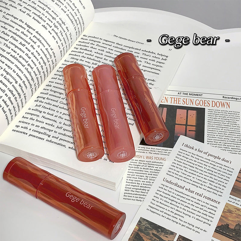 Three Gege bear lip glosses on an open book with visible text.