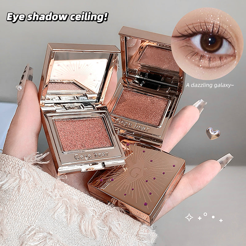 Makeup compact with rose gold finish held by a hand, showing eye shadow and close-up of an eye.