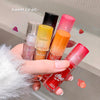 Hand holding five colorful lip balms with visible brand names against a neutral background