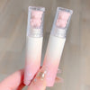 Two gradient lip glosses with bear-shaped caps held by a hand against a neutral background