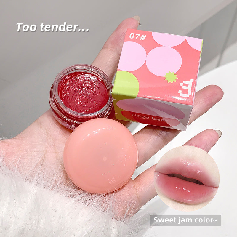 Hand holding a small container of red lip balm, a pink lip balm, and a box labeled 'Gege bear' with text 'Too tender.