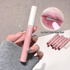 Pink lip gloss held by a hand with a close-up of lips wearing the gloss and additional lip glosses in the background.