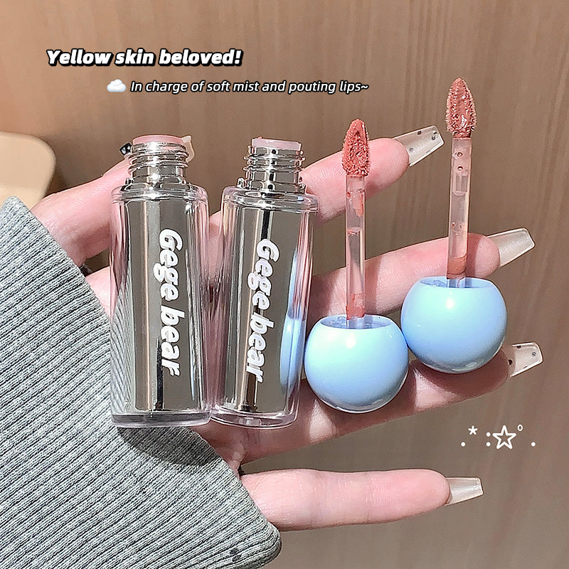 Two clear lip gloss bottles with blue caps held by a hand, with 'gege bear' branding.