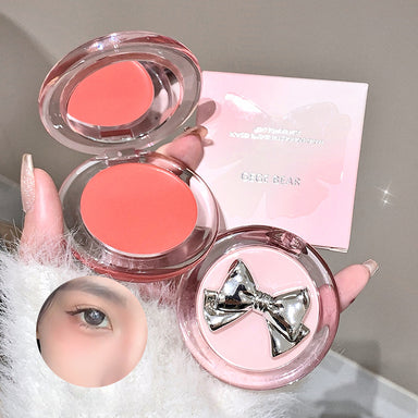 Makeup product with pink blush and decorative bow on a neutral background
