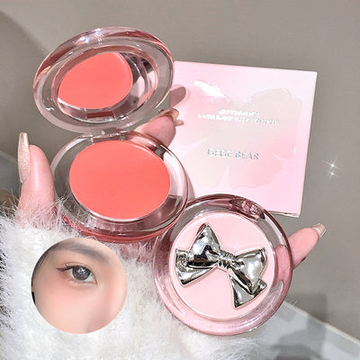 Makeup product with pink blush and decorative bow on a neutral background