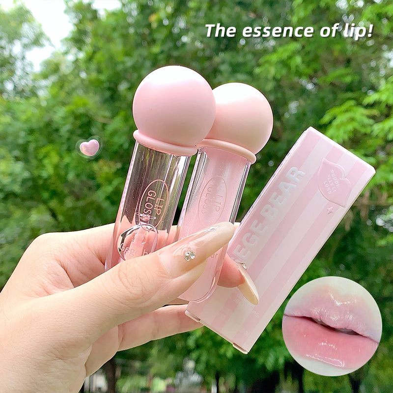 Pink lip balm with clear cap held by a hand against a green outdoor background