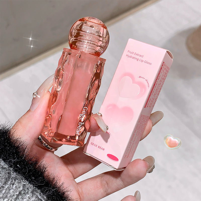 Pink lip gloss with packaging held in a hand on a light background