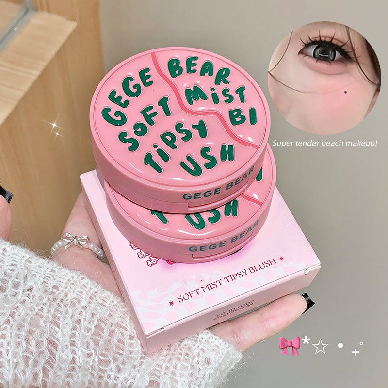 Pink makeup product with 'GEGE BEAR' text held by a person, with an inset of a close-up of a eye wearing the product.