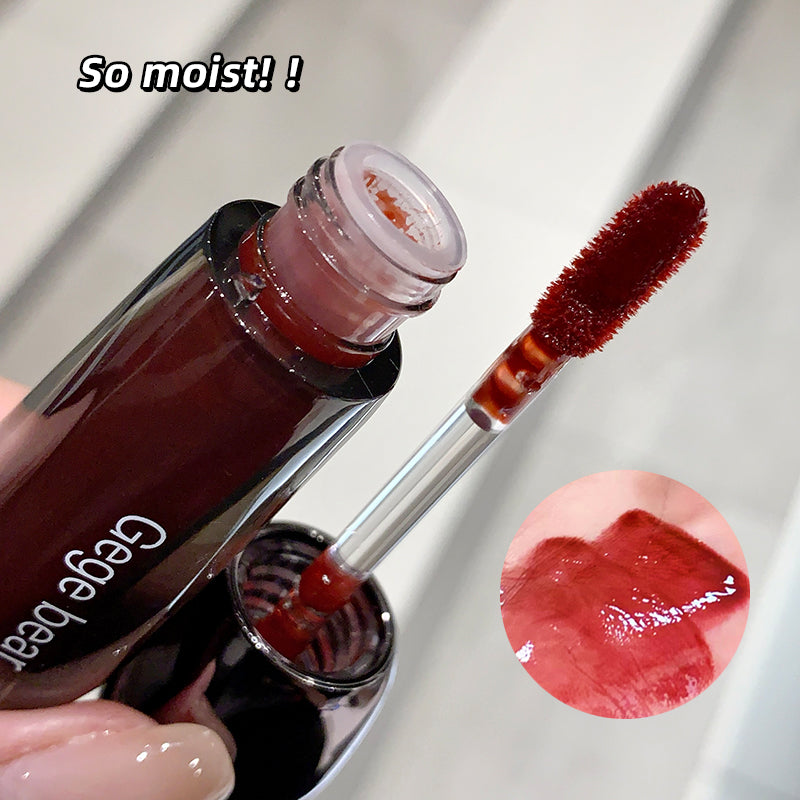 Lip gloss with applicator and close-up of color on a white background