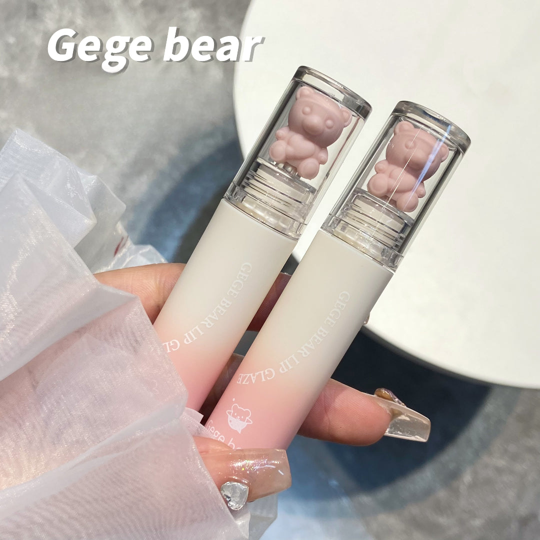 Two lip glosses with bear-shaped ends held by a hand, branded 'Gege bear'.