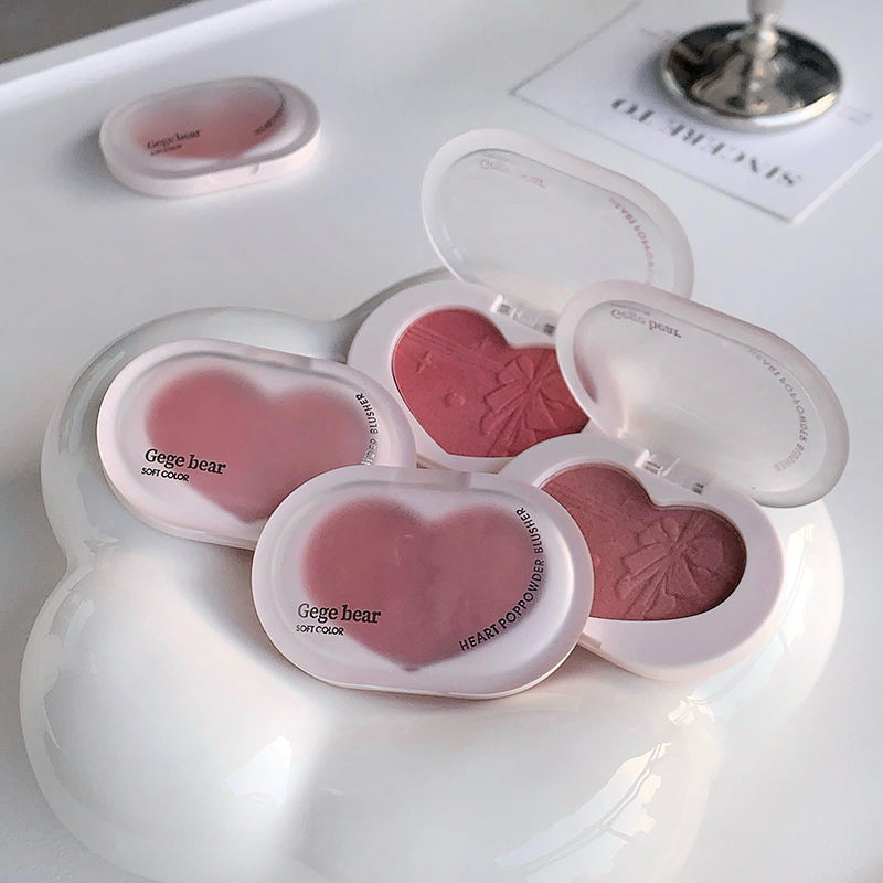 Heart-shaped blush compact with pink blush in multiple shades on a white surface.