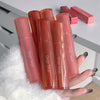 Multiple Gege Bear lip glosses held by a hand on a white surface