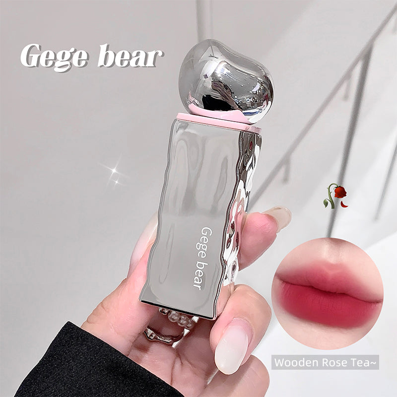 Clear lip gloss with pink cap held by a hand, 'Gege bear' branding visible.
