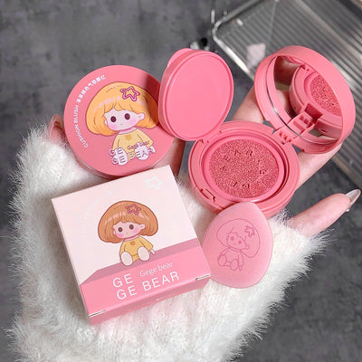 Pink compact powder with cartoon character design on a gray surface