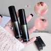 Two black lipsticks held by a hand with a close-up of a lip wearing one of the lipsticks.
