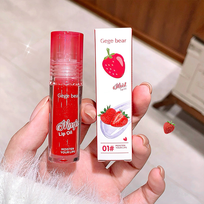 Red lip oil with packaging held in a hand, against a neutral background