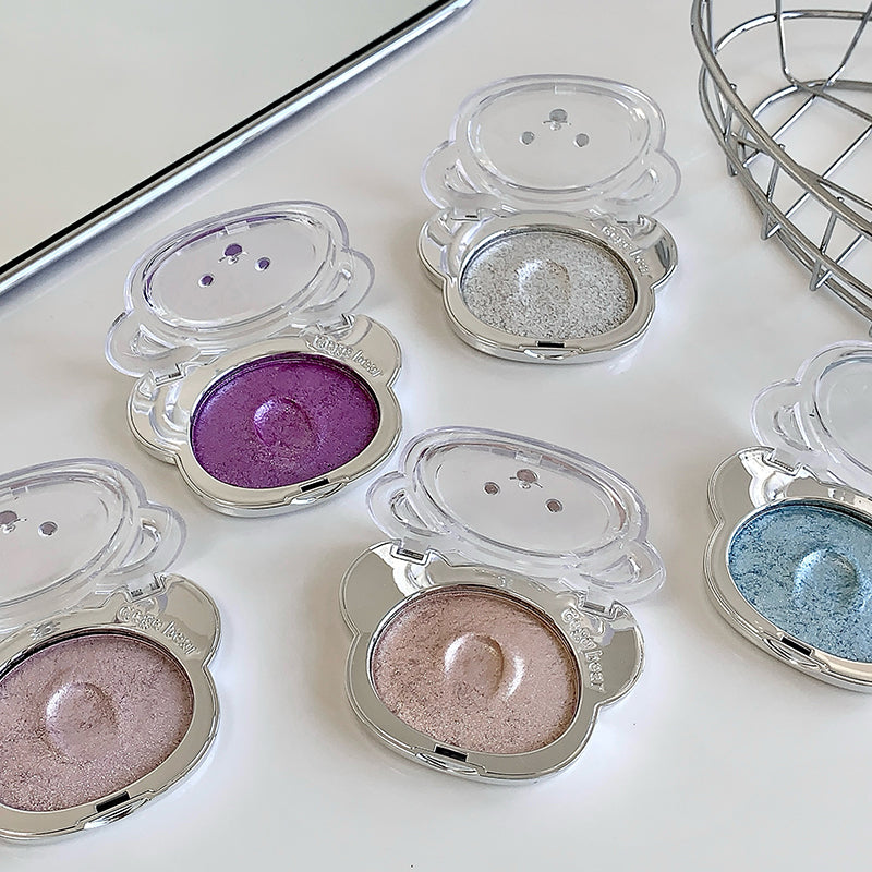 Compact eyeshadows in various colors on a white surface