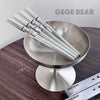 Metallic straws with 'GEGE BEAR' branding on a metallic stand against a white background.