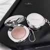 Makeup compact with pink glittery powder on a black surface, featuring the brand 'Gege bear'.