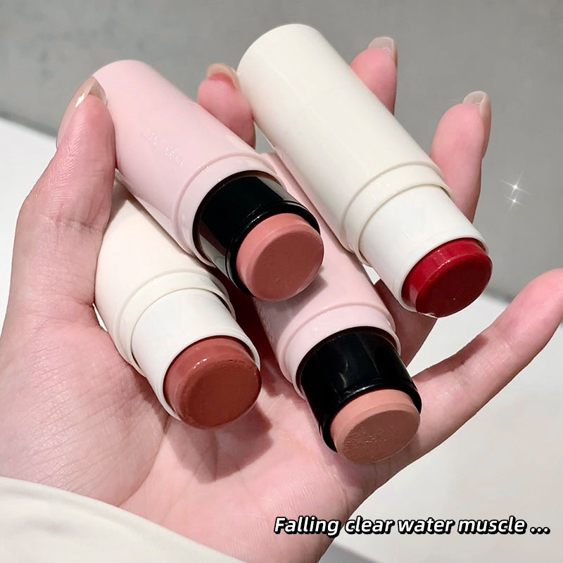 Hand holding three lip balms with visible color swatches on a neutral background